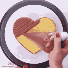 a person is icing a heart shaped cake on a plate