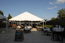 a white tent with tables and chairs underneath it
