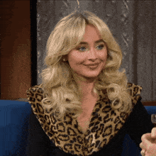 a blonde woman wearing a leopard print jacket smiles
