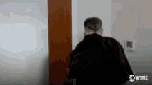 a man is standing in front of a door with a showtime logo on the bottom .
