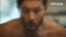 a close up of a shirtless man 's face with a countdown logo in the corner .