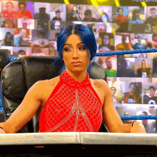 a woman with blue hair is sitting in a chair in front of a crowd