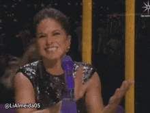 a woman sitting in front of a purple microphone with the username lialmeida05