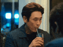 a man drinking from a glass with a straw in his mouth