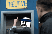 a man pointing to a sign that says believe