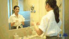 a woman is standing in front of a bathroom mirror .