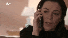 a woman is crying while talking on a cell phone with a hd logo behind her