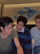 three young men are sitting on a bed and one of them is wearing a shirt that says ' aoi '