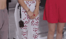 a woman in a red skirt is standing next to a woman in a white skirt with red cherries on them .