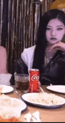 a woman is sitting at a table with a can of coca cola in front of her
