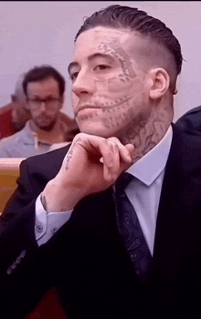 a man with a tattoo on his face is wearing a suit and tie ..