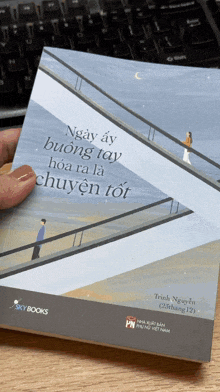 a person is holding a book titled ngày ấy buông tay hoa ra là chuyện tôi