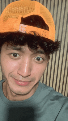 a man with curly hair is wearing an orange hat that says the north face on it