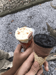 a person holding two ice cream cones one of which has a cookie on it