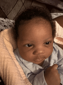 a baby with curly hair is laying on a blanket