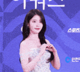a woman in a white dress stands in front of a blue background that says " a "