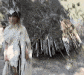 a woman in a white dress is standing in front of a pile of sticks