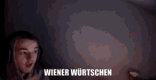 a person wearing headphones says wiener wurtschen in front of a dark background