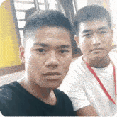 two young men are posing for a picture together while sitting next to each other in a room .