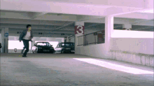 a man is running through a parking garage with a red pillar that says 3 on it
