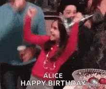 a little girl is dancing at a birthday party while wearing a santa hat .