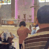 a group of people praying in a church with a purple wall