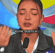 a woman is talking into a microphone and the words kuya gusto ko are on her face