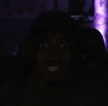 a close up of a person 's face in the dark with a purple background .