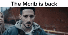 a man with a beard is standing in front of a red building with the words `` the mcrib is back '' .