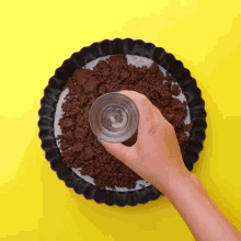 a person is holding a glass over a pan of brown crumbs