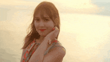 a woman in a floral dress is standing on a beach at sunset