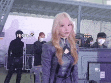 a woman wearing a purple jacket stands in front of a computer monitor with a star on it