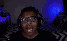 a man wearing headphones and glasses is screaming in front of a microphone with the word handle written on the screen .