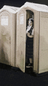 a woman in a plaid skirt is standing in a portable restroom