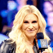 a woman with blonde hair is holding a microphone with a w on it