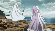 a man and a woman are standing next to each other on top of a hill . the woman is wearing a wedding dress .