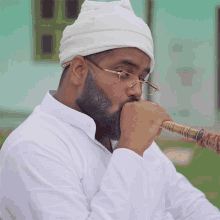 a man with a beard wearing glasses and a white head scarf