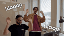 two men are waving their hands in front of a wall that says wooop on it