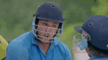 a young boy wearing a cricket helmet looks at the camera