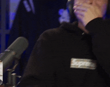 a man wearing headphones and a black sweatshirt with the word supreme on the front