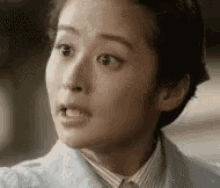 a close up of a woman 's face with a striped shirt and a blue jacket .