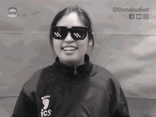 a woman wearing sunglasses and a black jacket with the word ics on it
