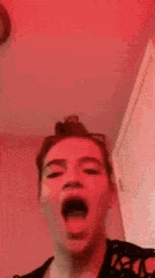 a young man is making a funny face with his mouth open and his hair in a bun .