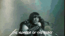 a man singing into a microphone with the words " the number of the beast " above him