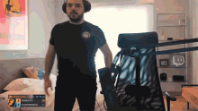a man wearing headphones stands in front of a microphone in a room with a twitch logo in the corner
