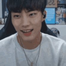 a young man wearing headphones and a necklace smiles at the camera .