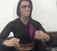 a woman wearing glasses and a black shirt is sitting on a chair .