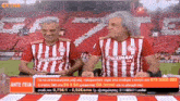 two men wearing red and white striped shirts with stoiximan on them