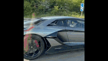 a gray lamborghini aventador is driving down a road .