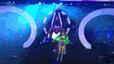 a woman in a green and yellow outfit is standing on a stage in front of a sign that says a on it